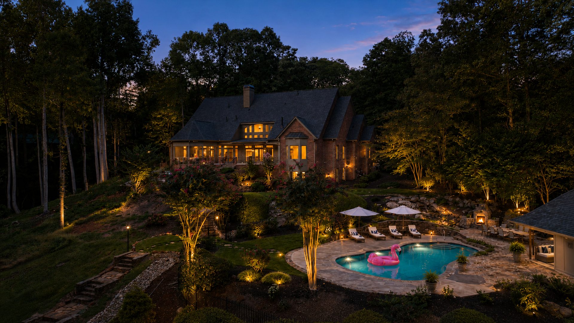 120 Tuscany Way at twilight, pool and terraced grounds lit against the creek